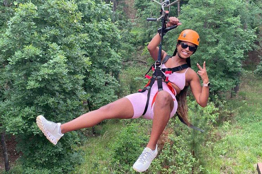 girl ziplining smiling and giving peace sign